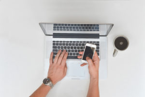 Mans Hands Woking On Laptop And Smartphone With Coffee